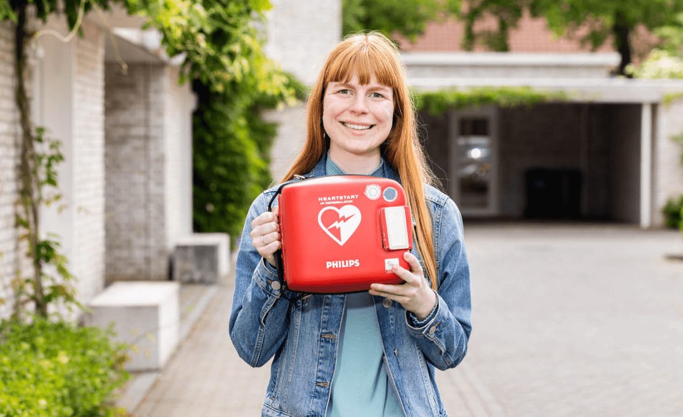 Vrouw poseert met Philips Heartstart in een woonwijk