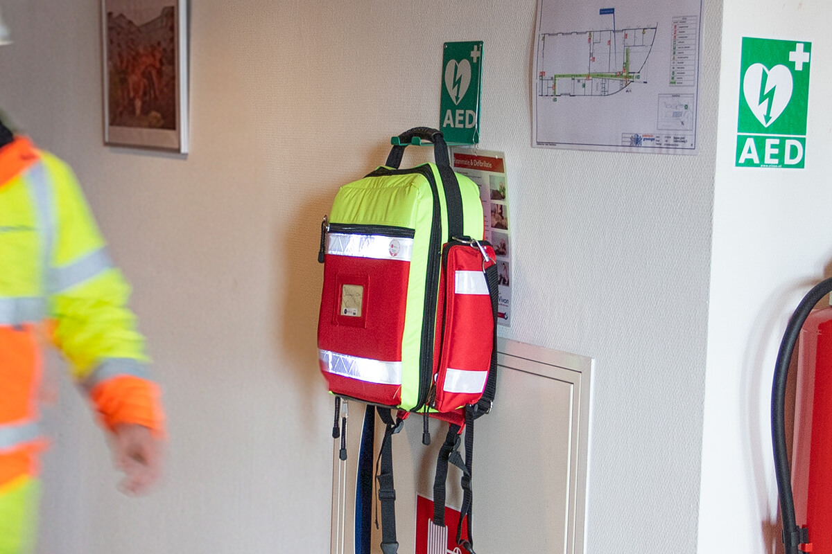Een tas met AED hangt aan de daarvoor bestemde beugel in een gang