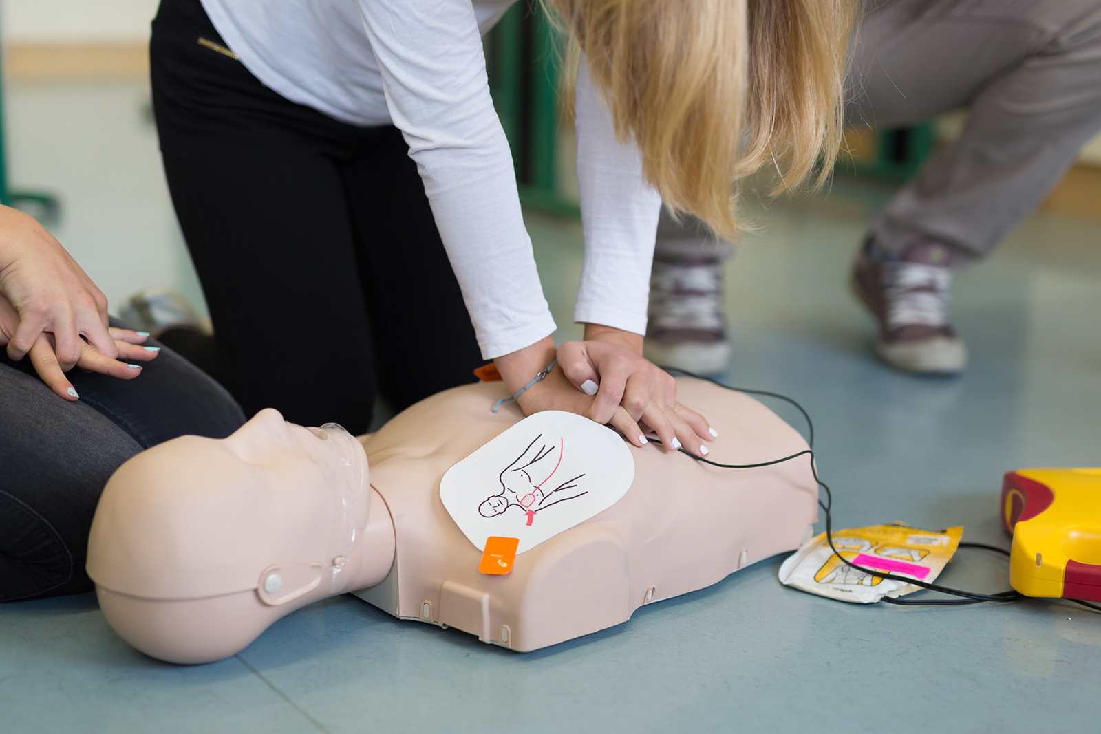 Vrouw krijgt instructie en leert reanimeren op een reanimatiepop