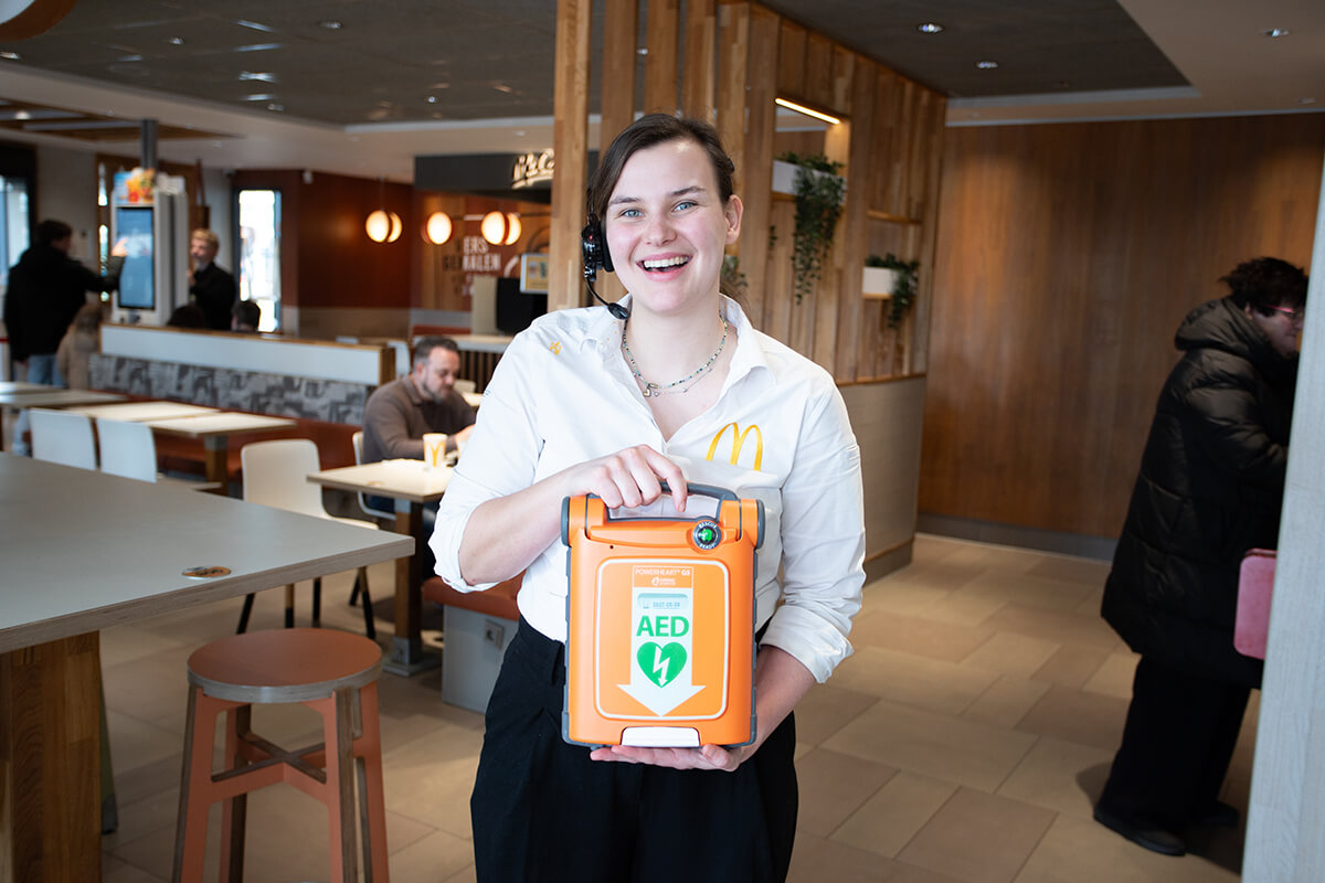 Een medewerker van MacDonalds poseert in het restaurant met een AED