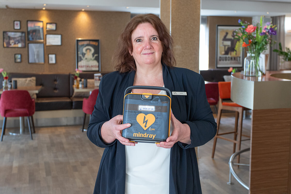 Receptioniste van een hotel poseert met een Mindray L1 AED in de ontbijtzaal
