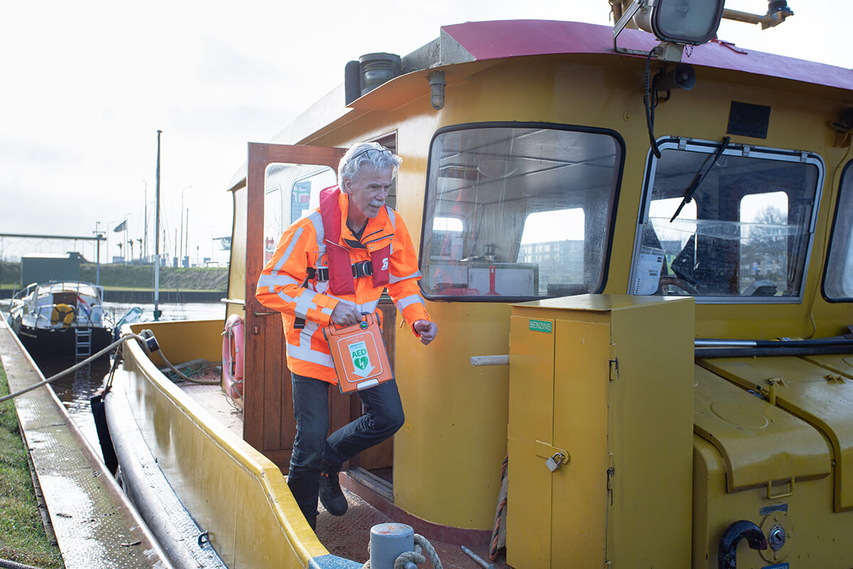 De kapitein van een werkschip rent met en AED over het dek
