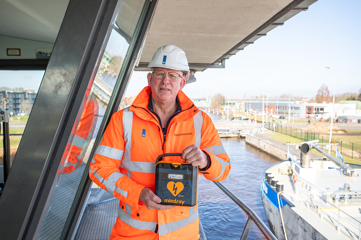 Een medewerker van rijkswaterstaat poseert met een Mindray L1 AED op een sluis