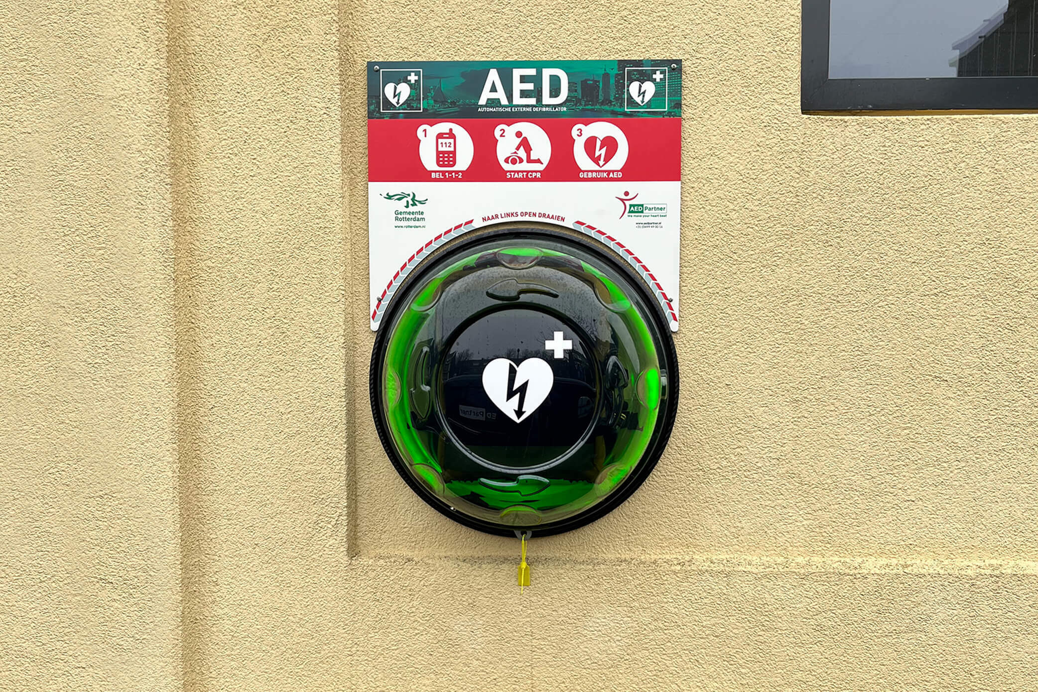 Een nieuwe AED hangt aan een muur in gemeente Rotterdam