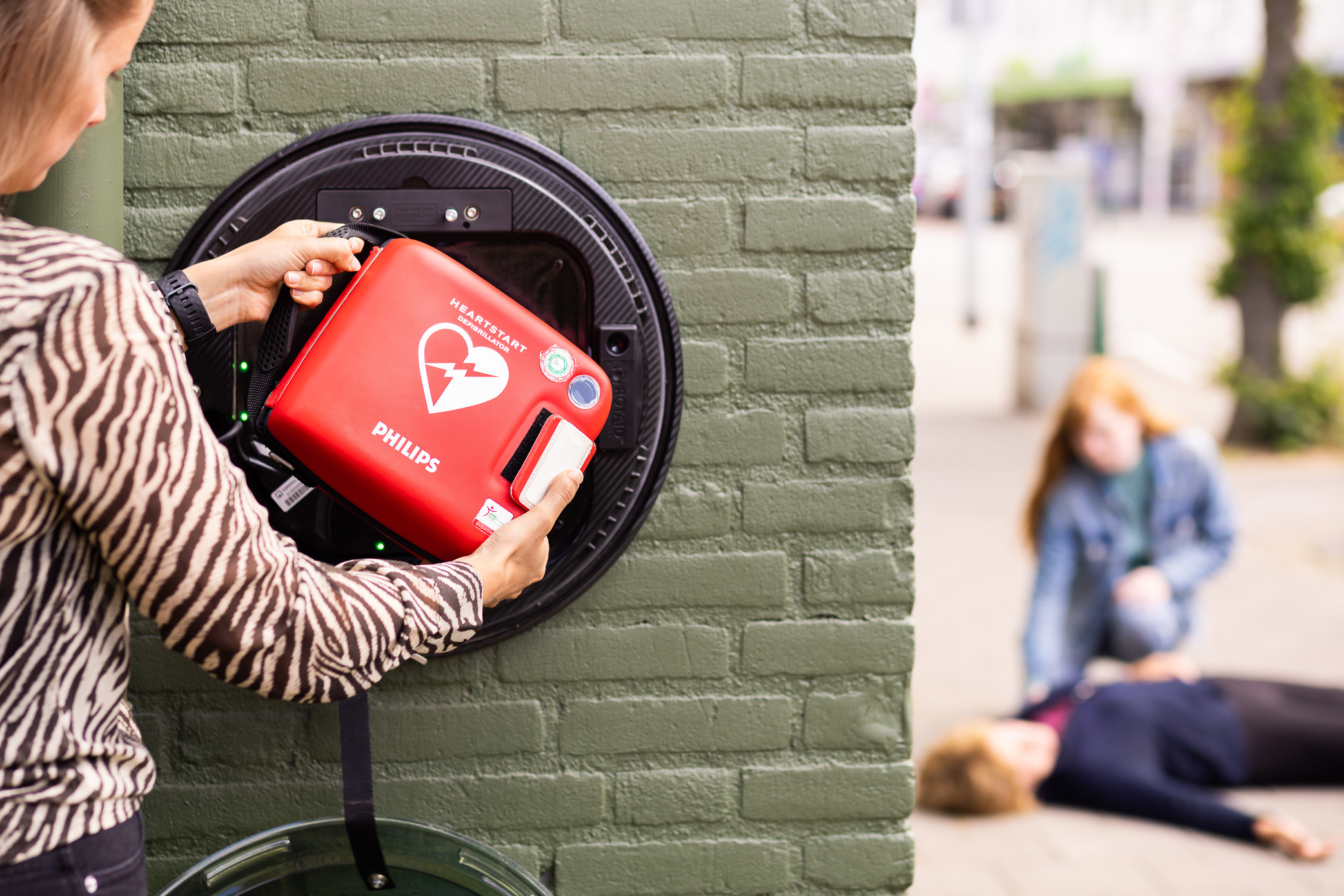 Vrouw haalt AED uit kast voor een medische situatie