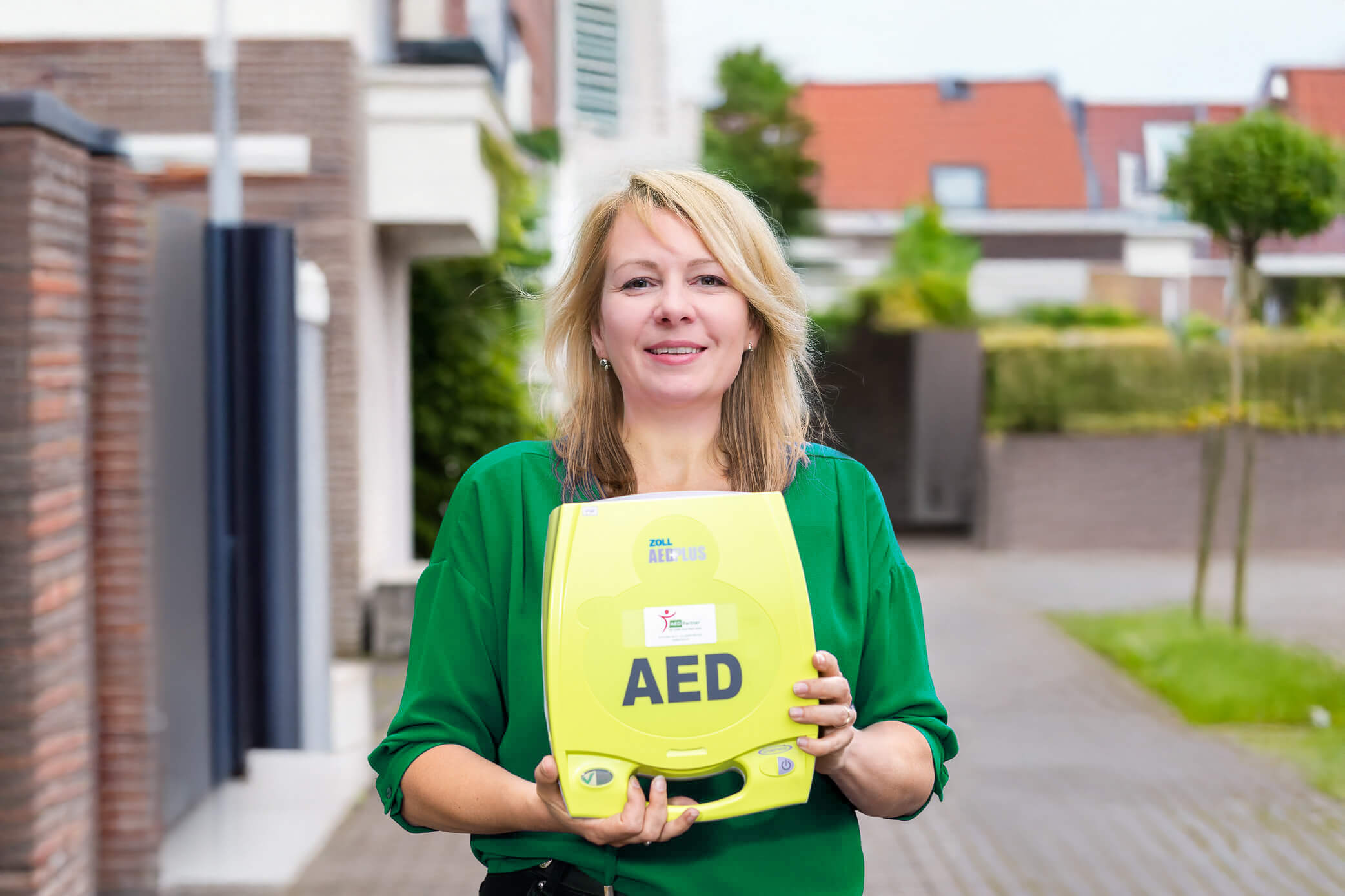 Vrouw poseert met Zoll AED+ bij haar huis