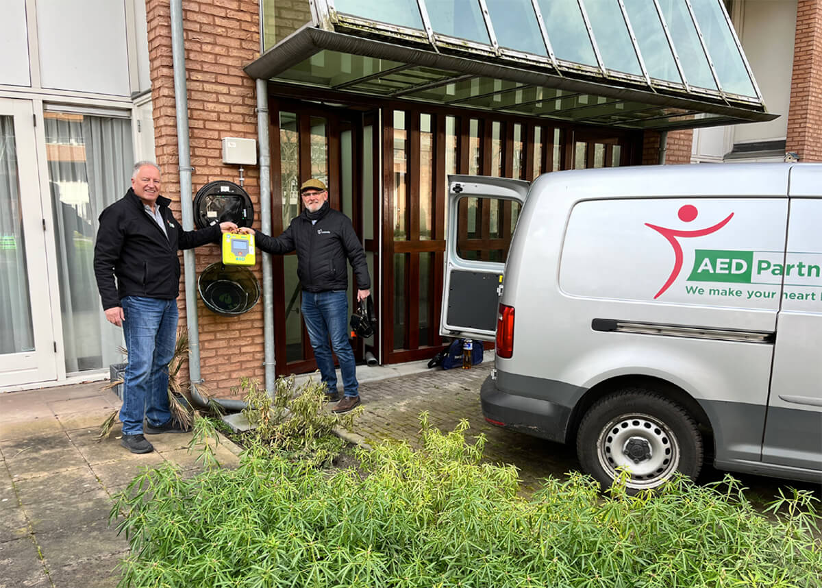 Medewerker AED-Partner overhandigt een AED aan Vesteda