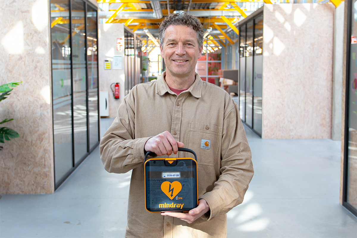 Man poseert met Mindray L1 AED in de gang op kantoor