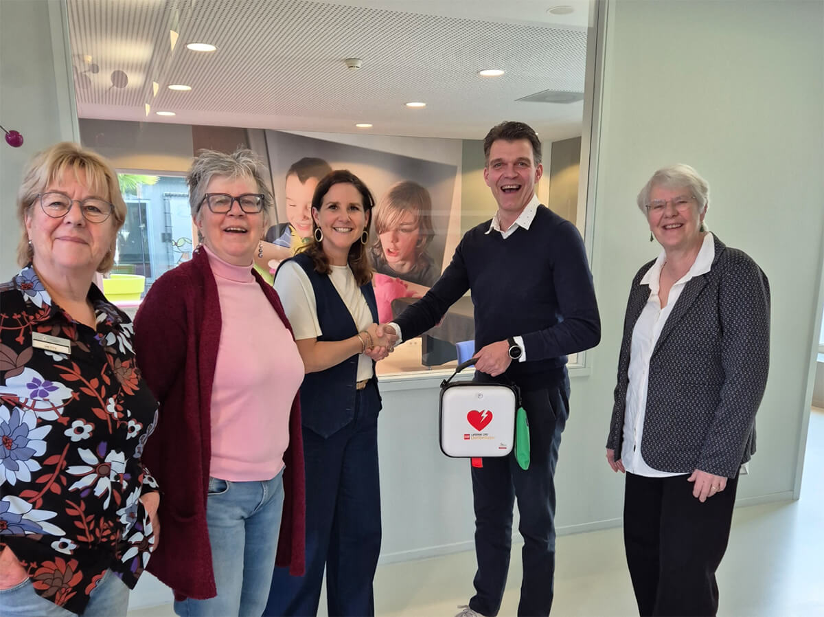 Medewerker AED-Partner overhandigt een AED aan het Ronald mcDonalds Boshuus